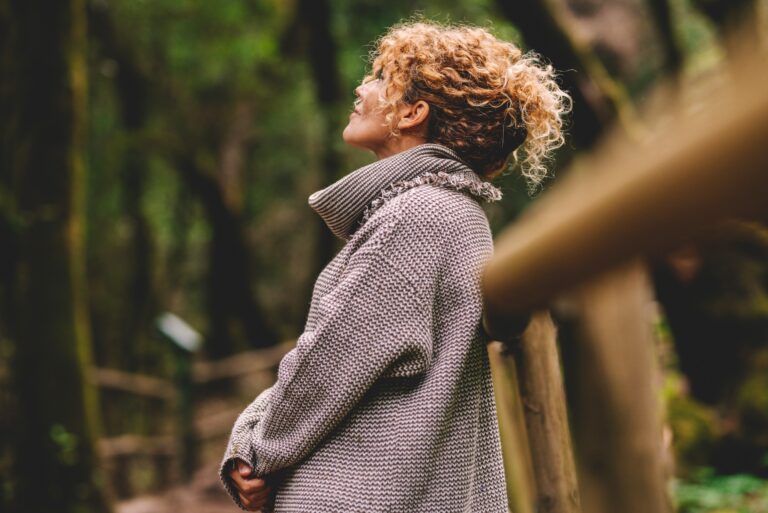 Side portrait of woman relaxing in the nature. Inner balance and mindfulness concept moments. Standing female people in the woods enjoying silence and good nature vibes alone smiling and admiring